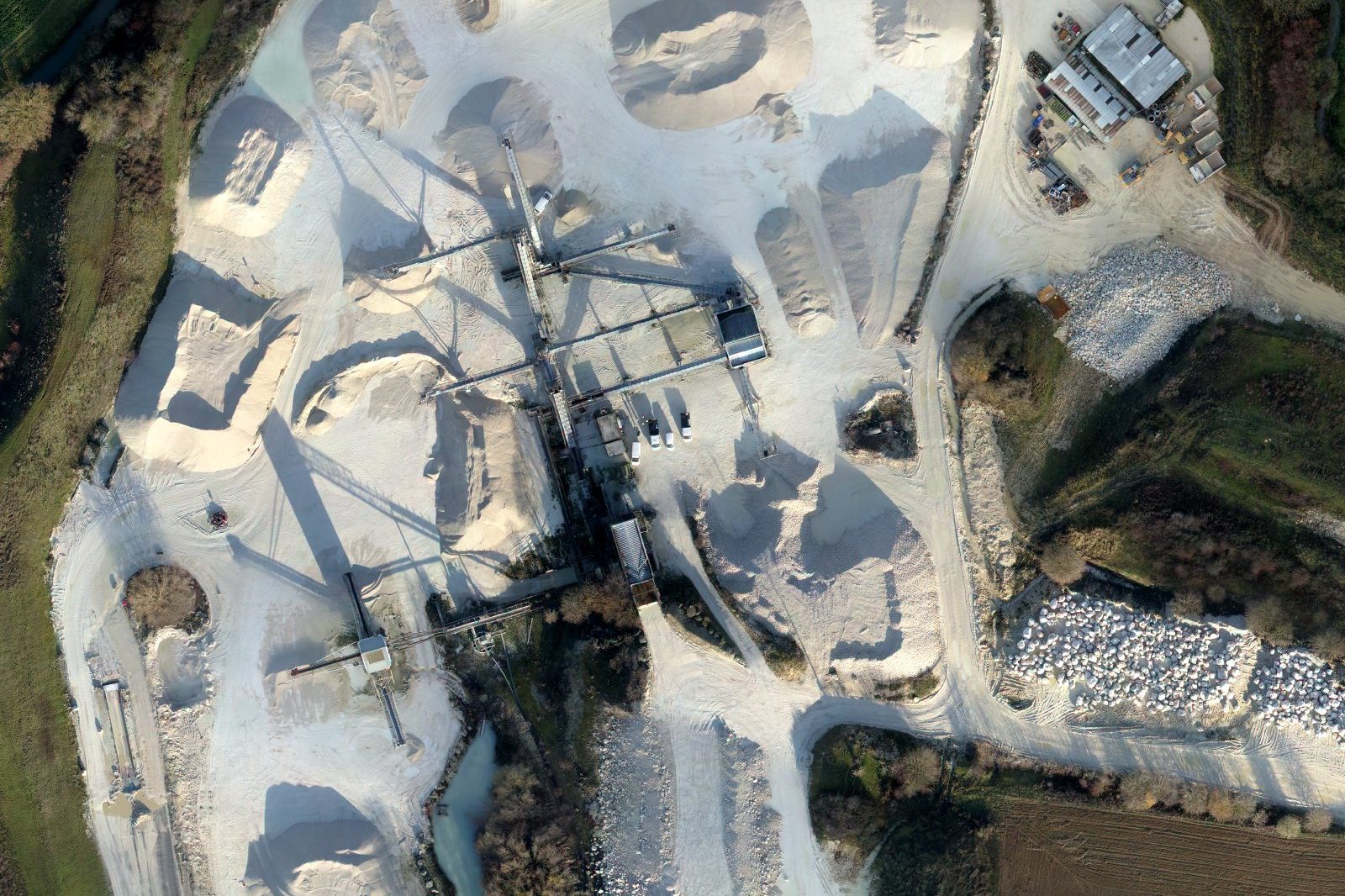 Plateforme de stocks d'une sablière vue par drone : tas de sables et de graviers, convoyeurs, installation de traitement