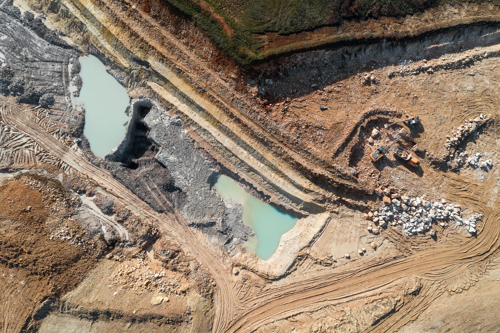 Vue verticale par drone d'un chantier de terrassement : talus, bassins, pistes, pelles et tombereaux