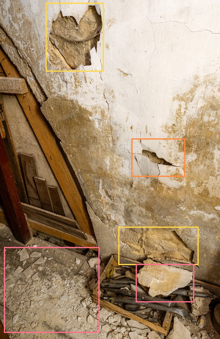 Plaster fallen at the top of a wall, cracked and bulging plaster, pieces of plaster on the floor